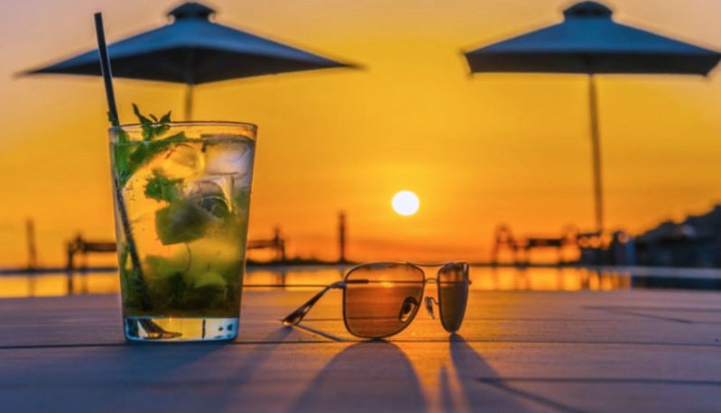 A picture of a cocktail with the sunset behind