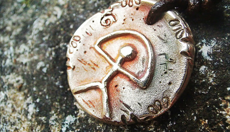 A picture of an Indalo Man symbol embossed on a silver talisman