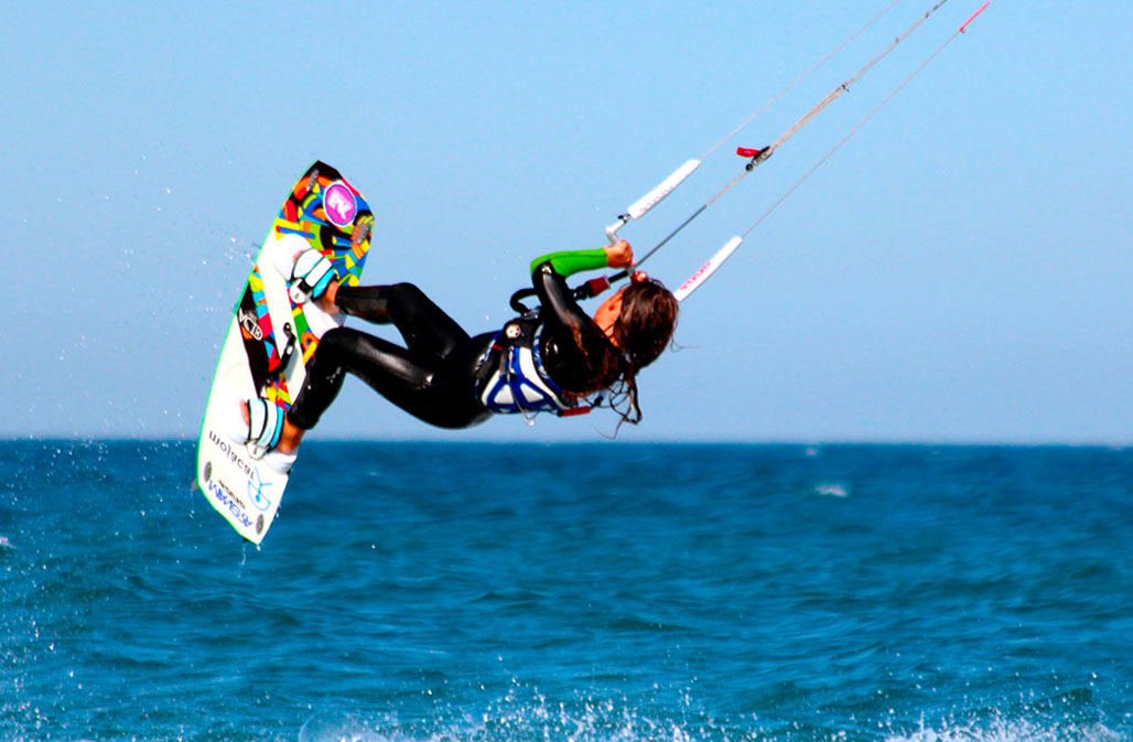 The image captures an exhilarating moment of a kiteboarder soaring over Mojacar's blue waters, demonstrating the thrilling outdoor activities the region offers.