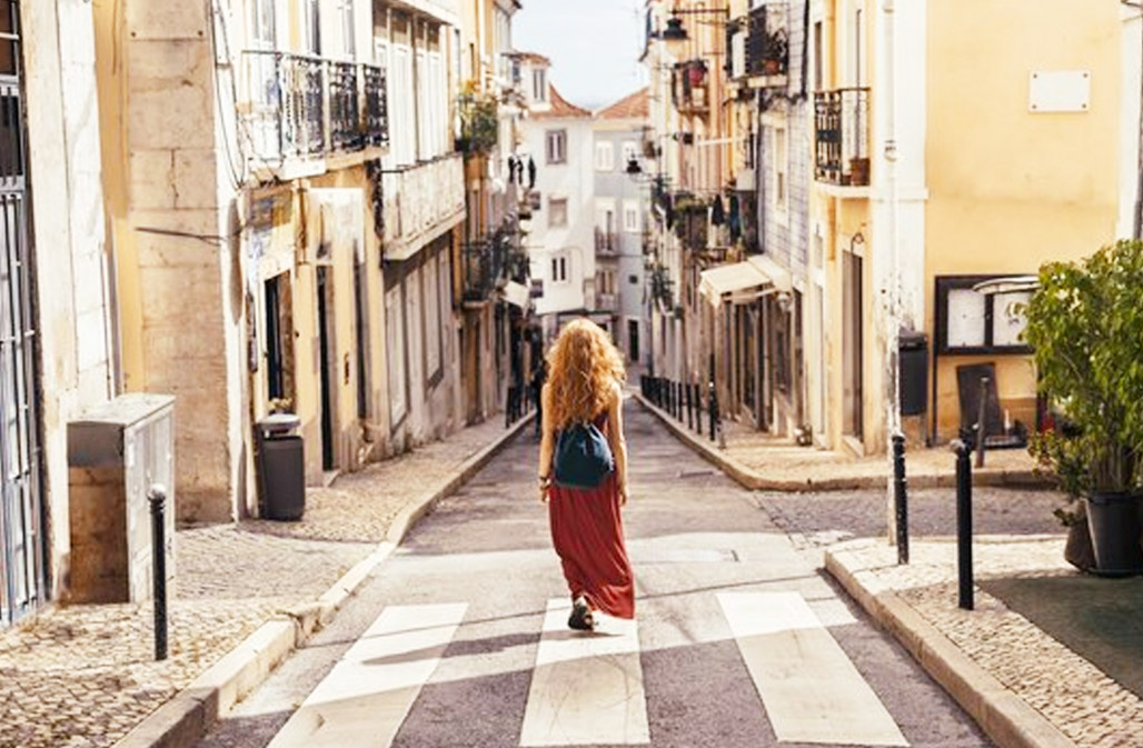 A picture of a woman walking through narrow Spanish streets to reach the local market.