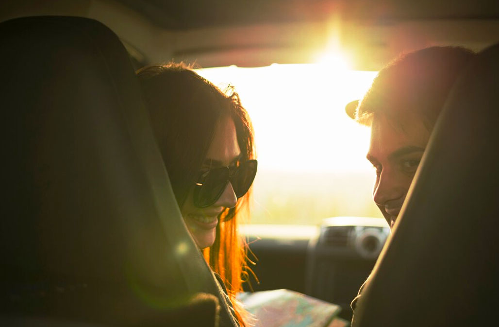 Two individuals smiling inside a car, bathed in the warm sunset light in Mojácar, Spain.